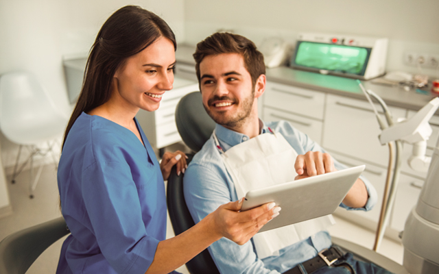 Man smiles while dentist shows him something on a tablet