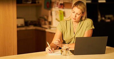 Woman taking notes while on sitting in front of a computer