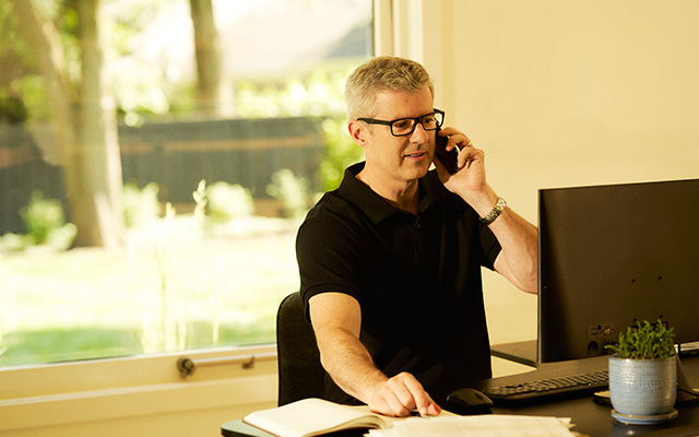 Man talking on phone while sitting in front of computer