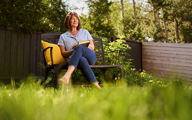 Woman sitting on park bench with a book
