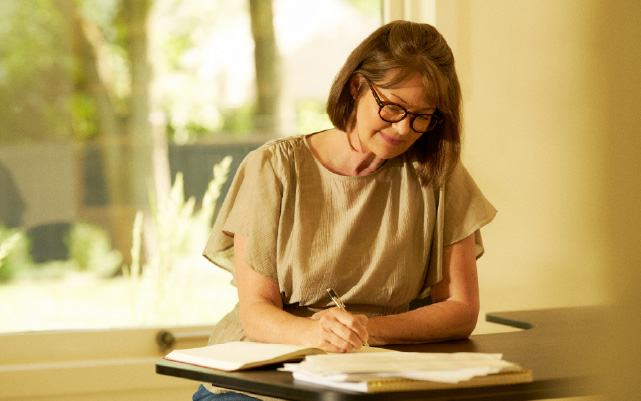 woman sitting at a desk writing in a notebook.