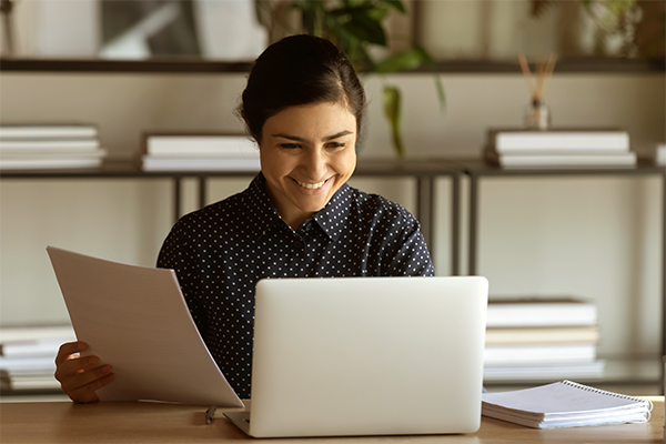 Woman smiling while looking at computer and holding file