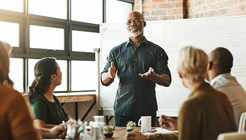 Man presenting in front of conference table of people